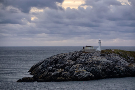 Lighthouse on the rocky Atlantic Ocean Coast during a cloudy sunset. Taken in Channel-Port aux Basques, Newfoundland, Canada.