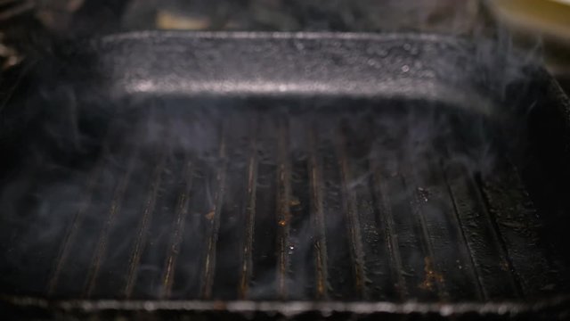 Freshly cooked Tibon steak is taken from a hot grill pan using steel tongs. Delicious roasted piece of veal. Frying meat close up. Delicious fatty junk food.