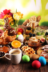 breakfast on table with bread buns, croissants, coffe and eggs
