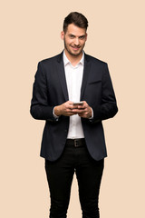 Handsome business man sending a message with the mobile over ocher background
