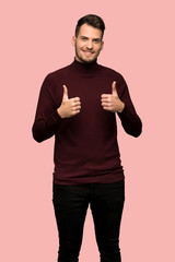 Man with turtleneck sweater with thumbs up because something good has happened over pink background