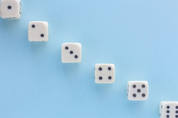 White gaming dices on light blue background. victory chance, lucky. Flat lay, place for text. Top view. Close-up. Concept gamble. spectacular pastel