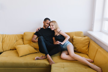 Couple hugging with eyes closed on the couch. Lovers holding hands, hugging. Happy faces, warm relationship, love, romance.