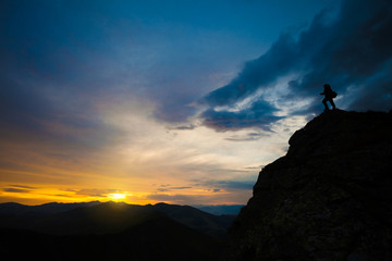 Photographer on top of steep rocks photographing sunset