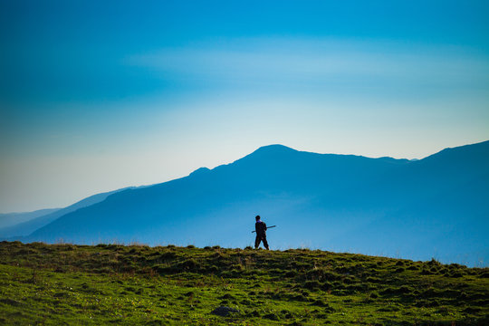 Shepherd Walking Holding A Rod In His Hands, Mountain Landscape