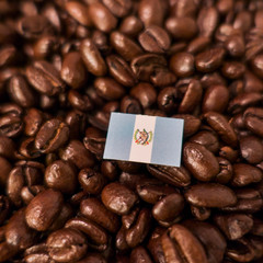 a Guatemala flag placed over roasted coffee beans