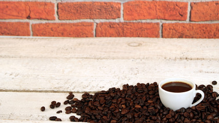 Coffee cup and coffee beans on white wooden table. 