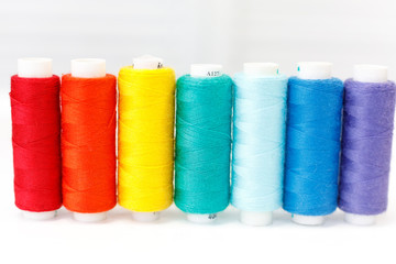 a row of spools of thread. rainbow colors