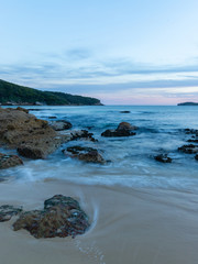 Fototapeta na wymiar Water motion at the beach shore around the rocks.