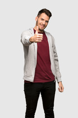 Man with sweatshirt with thumbs up because something good has happened over grey background