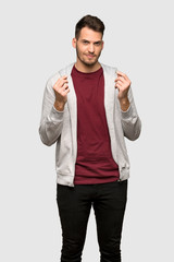 Man with sweatshirt making money gesture over grey background