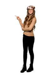 Obraz na płótnie Canvas Full-length shot of Young woman with beret pointing finger to the side in lateral position on isolated white background
