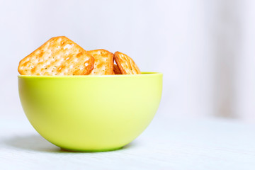 Crispy square cracker in a green plastic bowl