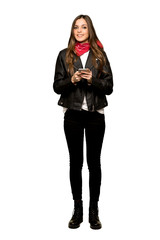 Full-length shot of Young woman with leather jacket sending a message with the mobile on isolated white background