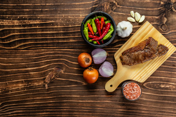 steak bifé on wooden board and spices on wood