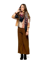 Fototapeta premium Full-length shot of Young hippie woman keeping a conversation with the mobile phone on isolated white background