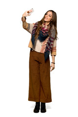Full-length shot of Young hippie woman happy and pointing the mobile on isolated white background