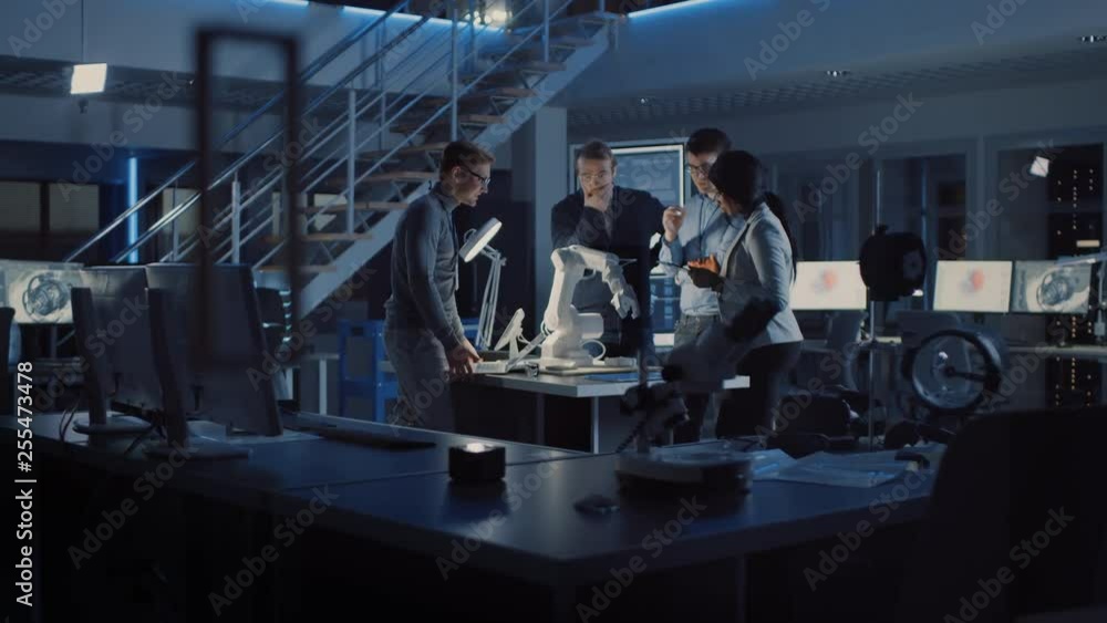 Poster Team of Electronics Development Engineers Standing at the Desk Working on Robot Arm Prototype. Specialists Working on Ultra Modern Industrial Design, Using Tablet Computer, Laptop.