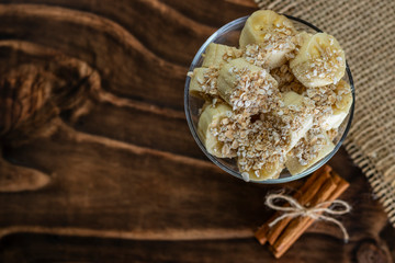 close up on glass jar with pieces of banana with oats, Wooden and jute Background
