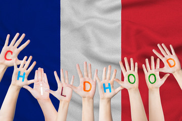 Childhood inscription on the children's hands against the background of a waving flag of the France