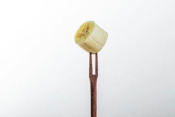 close-up on piece of banana spiked on small wooden fork