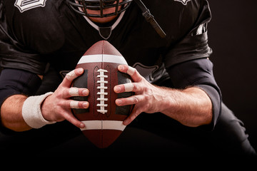 American football sportsman player on stadium with lights on black background.