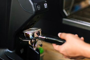 Morning coffee, Professional barista grinding coffee into portafilter to make espresso hot drink. Focus selection