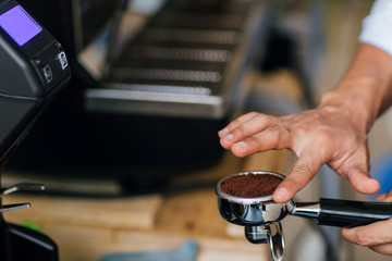 Morning coffee, Professional barista grinding coffee into portafilter to make espresso hot drink. Focus selection