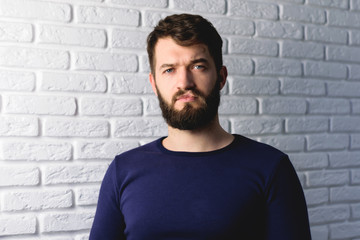 Fototapeta premium portrait of a handsome bearded man on brick wall background. Pensive hipster isolated