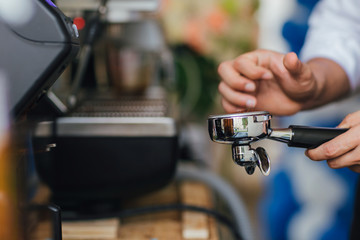 Fototapeta na wymiar Morning coffee, Professional barista grinding coffee into portafilter to make espresso hot drink. Focus selection