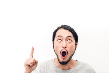 Portrait of happy smiling asian young handsome man surprised face expression cheering and pointing to empty copy space isolated on white background