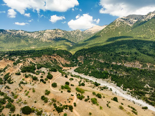 Fototapeta na wymiar Aerial view of serpentine road snaking between mountains in West Greece. A road full of twists and turns winding sharply up the mountain in Peloponnese region, Greece.