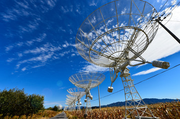 Array of satellite dishes or radio antennas against sky. Space o