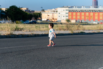 Niño pequeño jugando en carretera desierta 04