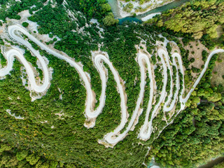 Aerial top down view of serpentine narrow road leading to Vikos Gorge in Northern Greece. A road full of twists and turns winding up the mountain in Zagori region, Greece.