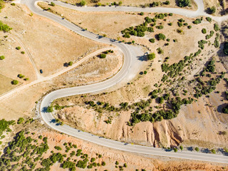 Aerial view of serpentine road snaking between mountains in West Greece. A road full of twists and turns winding sharply up the mountain in Peloponnese region, Greece.