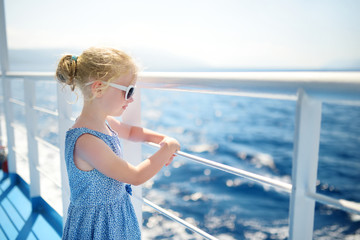 Adorable young girl enjoying ferry ride staring at the deep blue sea. Child having fun on summer family vacation in Greece.