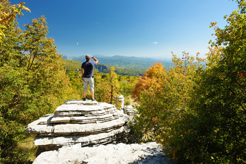 Male tourist exploring Stone forest, natural rock formation, created by multiple layers of stone, located near Monodendri village in Zagori region, Northern Greece.