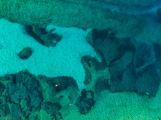 Aerial top down view of Emplisi Beach, picturesque stony beach in a secluded bay, with clear waters popular for snorkelling. Small pebble beach near Fiscardo town of Kefalonia, Greece.