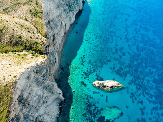 Scenic aerial top down view of picturesque jagged coastline of Kefalonia with clear turquoise waters, surrounded by steep cliffs.