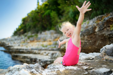 Cute little girl having fun at Emplisi Beach, picturesque stony beach in a secluded bay, with clear waters popular for snorkelling.