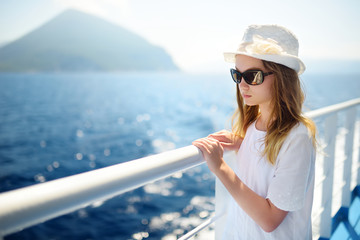 Adorable young girl enjoying ferry ride staring at the deep blue sea. Child having fun on summer family vacation in Greece.