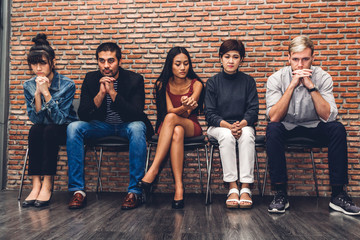 Group of business people while sitting on chair waiting for job interview against wall background