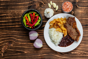 meal on white plate, rice, beans, steak and chips, Wooden Background