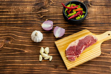 raw steak bifé on wooden board and spices on wood