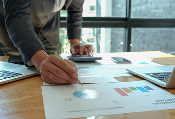 Hand businessman work on calculator and write graphs in the office.