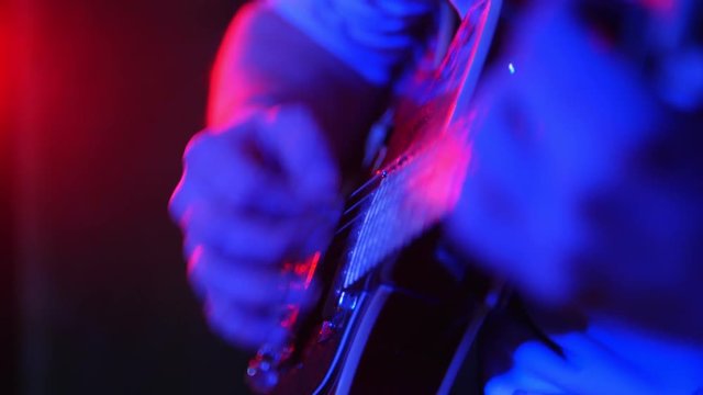 A person playing guitar in neon lighting