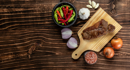 steak bifé on wooden board and spices on wood