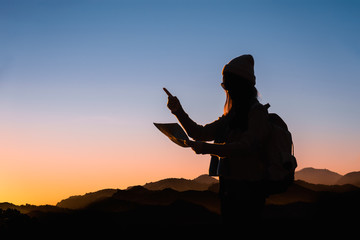 Traveler woman looking at the map with morning in mountains background.