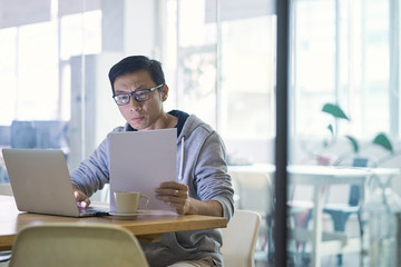 Fototapeta na wymiar Portrait of Asian businessman working on laptop in office